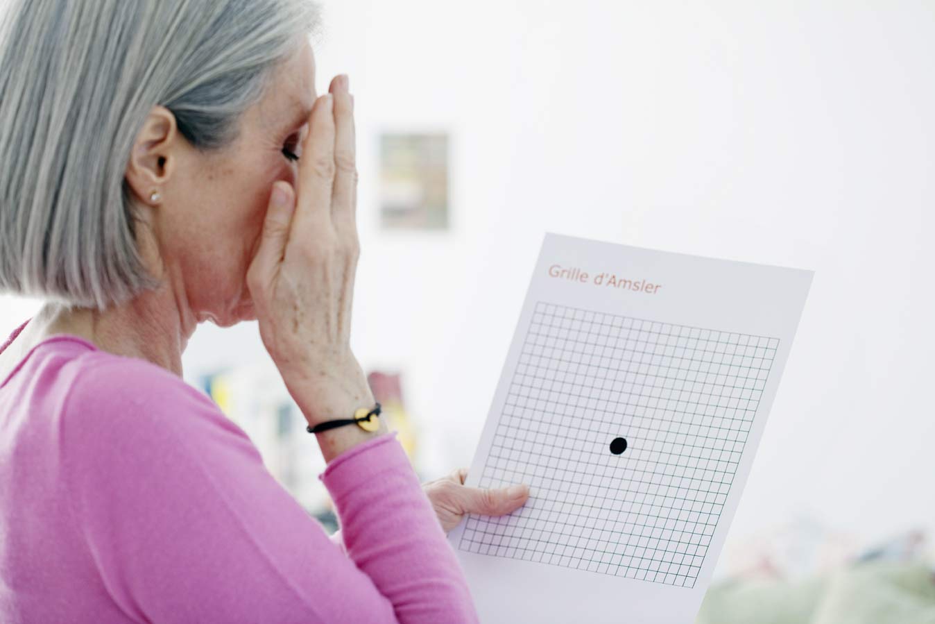 A 50 to 60 year old woman testing her vision with an macular degeneration grid